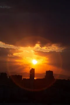 Construction crane at sunset on a background of orange sun, a city by the sea Stock Photos
