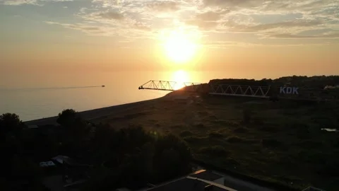 Construction crane on sunset background on seashore, drone flies past crane on Video stock 256599886