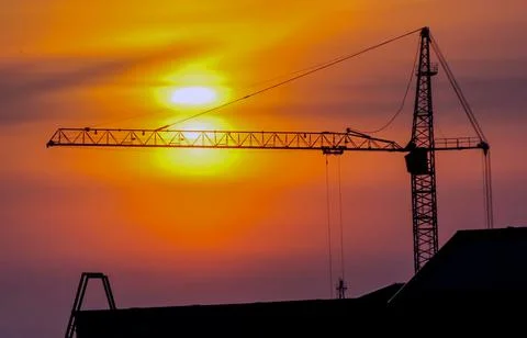 The construction crane on sunset. Construction crane at sunset, during the co Stock Photos