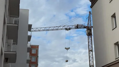 A construction crane is suspended between modern apartment buildings Stock Footage 313592890