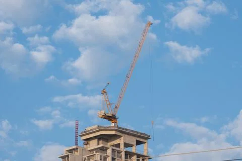 Construction crane on top of a building with blue sky Stock Photos