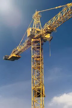 Construction crane tower in sun light beams on background of  blue sky. Crane Stock Photos