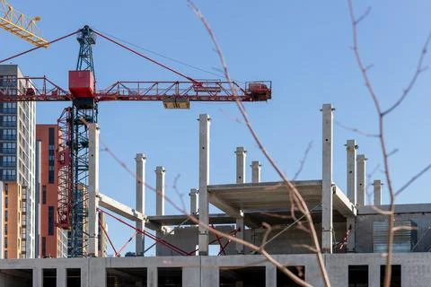 Construction crane towering above a building site with bare tree branches. .. 库存照片