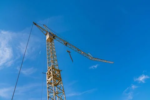Construction crane towering over a bright blue sky at the site Stock-Fotos