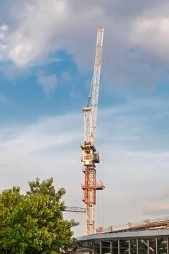 Construction crane towering over a building site with blue sky and clouds i.. Stock Photos