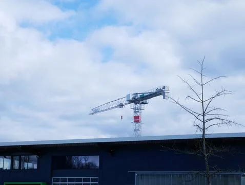 Construction crane towering over a modern building with a cloudy sky in the.. Fotos Stock