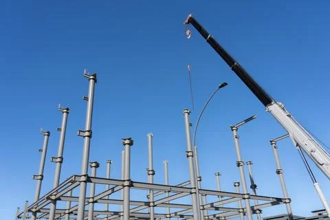 Construction crane towering over structural steel framing for new building Stock Photos