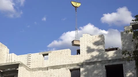 A construction crane transports a load to a construction site. An unfinished Stock-Footage 143666911