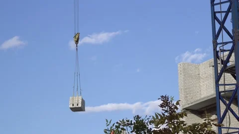 A construction crane transports a load to a construction site. An unfinished Stock-Footage 144357280