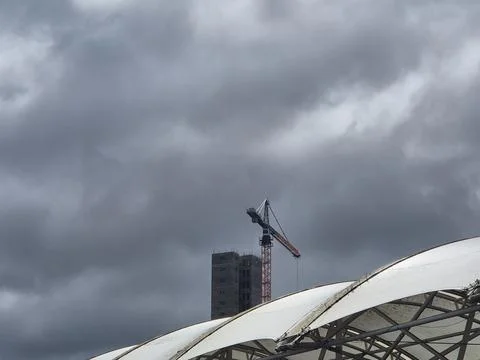 Construction crane under dramatic storm clouds Stock Photos
