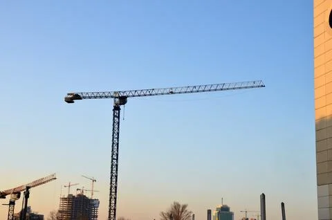 Construction cranes against clear evening sky Фото