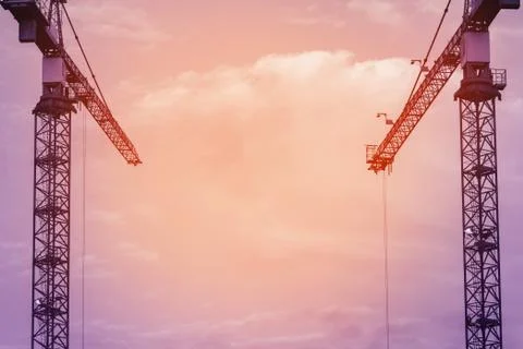 Construction cranes against the sky at sunset. Copy space. Fotos Stock
