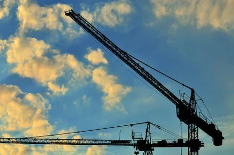 Construction cranes against of the sun Stock Photos