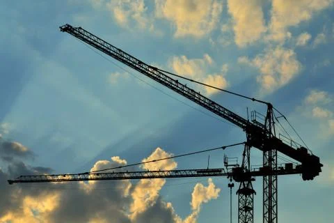 Construction cranes against of the sun Stock Photos