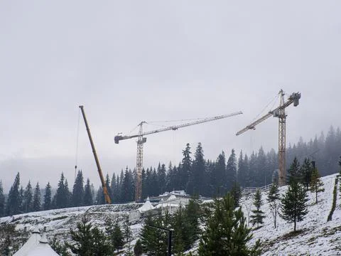Construction cranes among the mountains Stock Photos