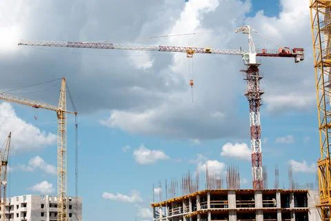 Construction cranes and building on construction site with cloudy blue sky Stock Photos
