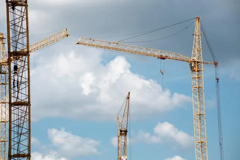 Construction cranes and building on construction site with cloudy blue sky Stock Photos