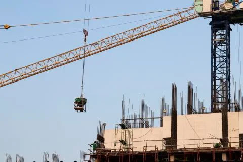 Construction cranes and construction workers on building site. Stock Photos
