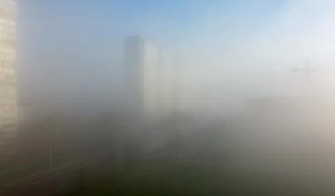 Construction cranes and a multi-storey residential building, shrouded in fog, Stock Photos