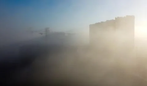 Construction cranes and a multi-storey residential building, shrouded in fog, Stock Photos