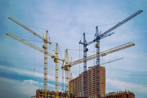 Construction cranes are erecting a multi-storey building. Stock Photos