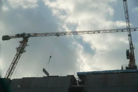 Construction cranes are under shade of light Stock Photos