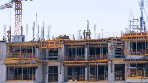 Construction cranes on the background of a building under construction with w Stock Photos