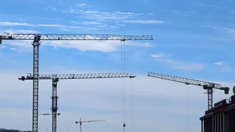 Construction cranes on a blue sky background. Industrial tower crane. Stock Footage 306660146