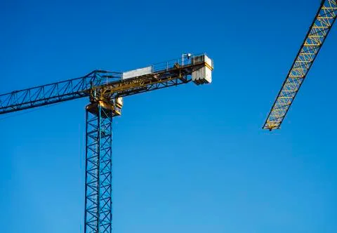 Construction cranes with a clear sky behind. Stock Photos