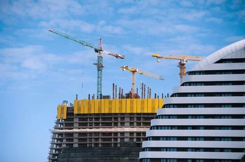 Construction cranes at the construction of a modern high-rise building Stock Photos