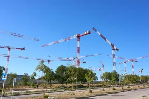 Construction cranes in a developing area under a clear blue sky Stock Photos