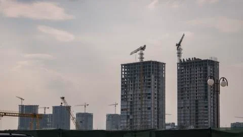 Construction cranes, houses in the distance. city landscape Stock Photos