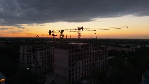 Construction cranes operate at sunset over urban building site in progress Stock Footage 339124288