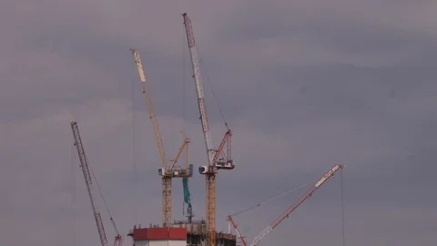 Construction cranes over tall skyscraper Stock Footage 104344748