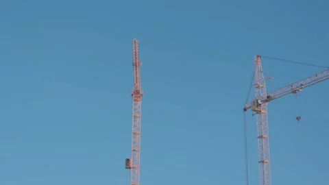Construction cranes rise against clear blue sky at a building site in the city d Stock Footage 328254357