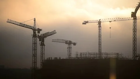 Construction cranes silhouetted against sunset sky Vídeo Stock 72264129