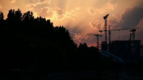 Construction cranes silhouetted against sunset sky Video stock 77156206