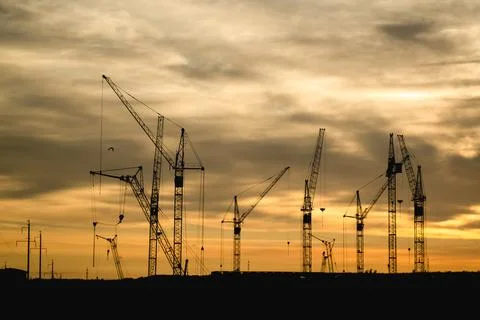 Construction cranes silhouettes at sunset sky Fotos Stock