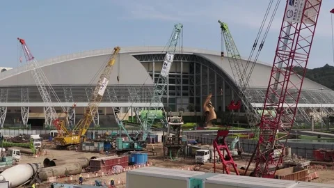 Construction cranes stand before a large domed stadium. Stock Footage 333690369
