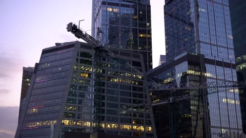 Construction cranes stand next to the skyscrapers. Skyscraper construction Stock Footage 115363647