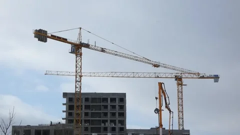 Construction cranes work on a building project in a city during daylight hours Stock Footage 330987581