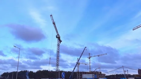 Construction cranes work on a building site during daytime with a clear sky and Stock Footage 323845260