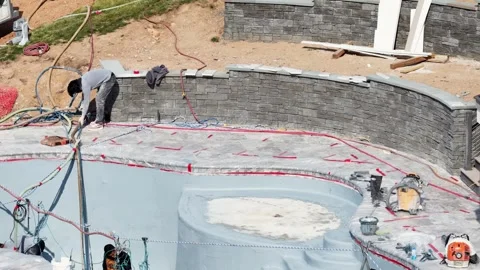 Construction crew applies pebble sheen coating inside curved swimming pool Stock Footage 339097935