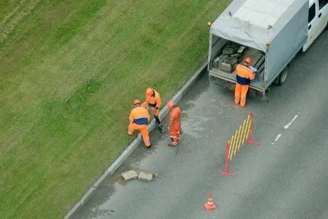 Construction crew of men working on road curb replacement. Aerial view of lab Stock Photos