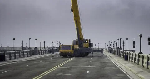 Construction crew operates heavy crane on urban bridge during cloudy day Stock Illustration