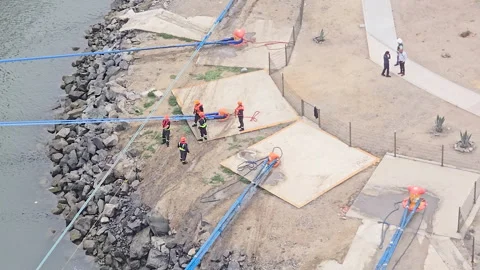 Construction crew with safety gear working on coastal reinforcement near Stock Footage 331073716