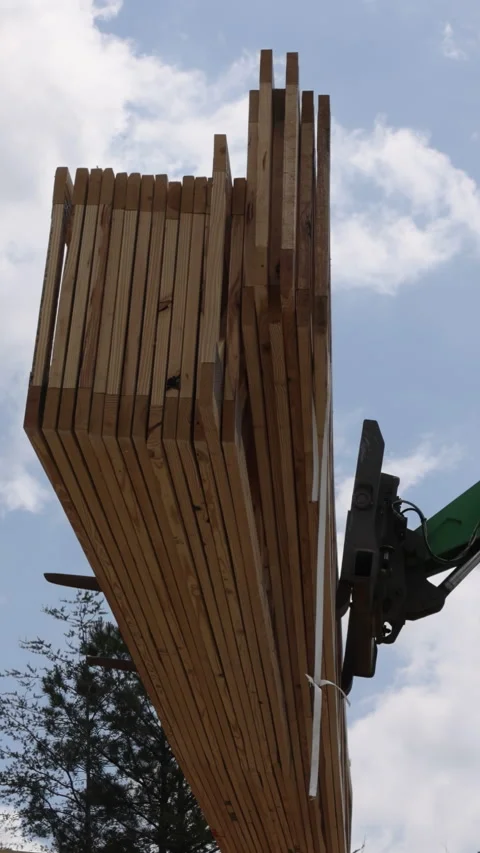 Construction crew uses crane to lift wooden truss for building frame on sunny Stock Footage 313668917
