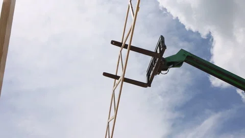 Construction crew uses lift to position joins frame scaffolding at building Vídeos de archivo 337498122