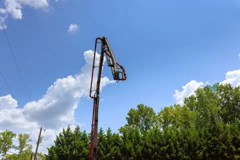 Construction crew using lift to work on tall structure under blue sky with Stock Photos