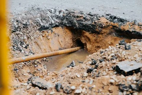 A construction crew is working on a utility pipeline at an excavation site. The Stock Photos